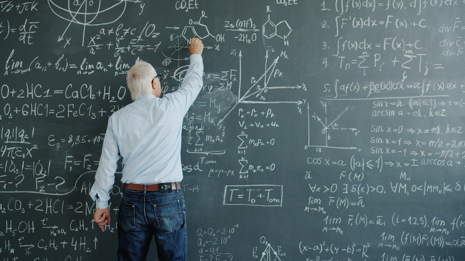 A professor writing complex formulas on a blackboard