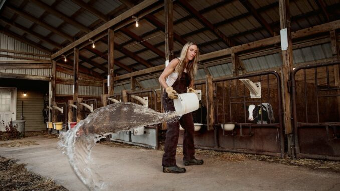 Woman pouring water outside of barn